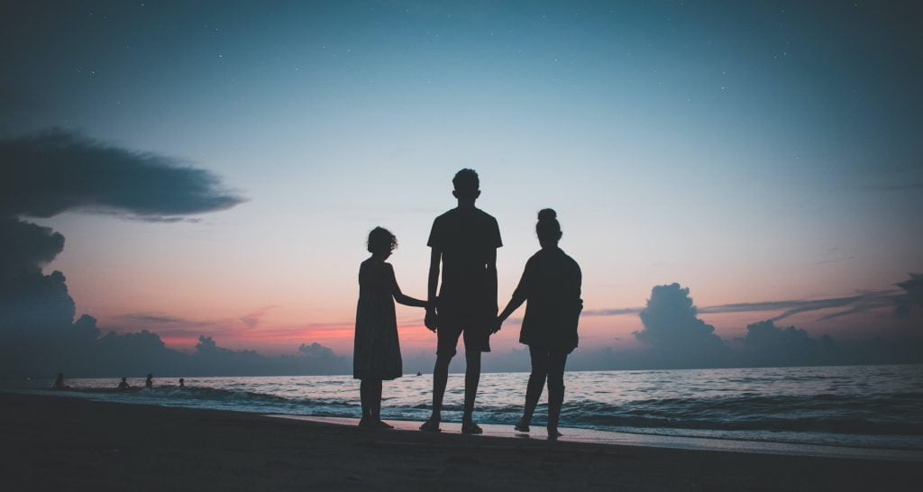 Familia unida en la playa durante el atardecer